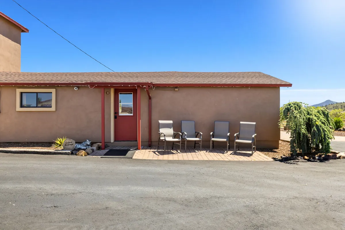 The cottage's inviting front porch, featuring comfortable outdoor seating and lush, landscaped plants. The view faces the setting sun, suggesting a welcoming space to relax and connect with loved ones while enjoying nature.