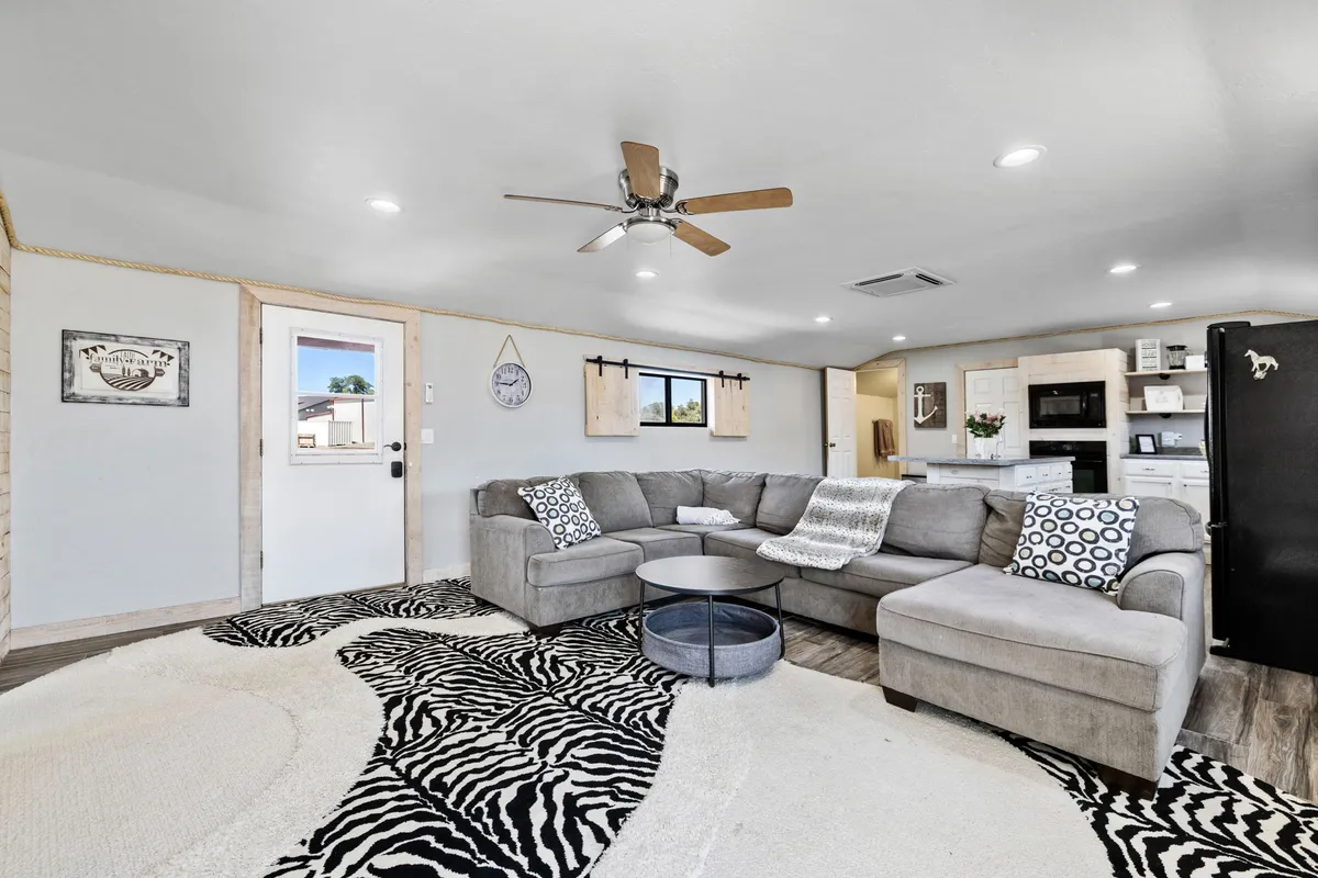This inviting interior features a cozy sofa set atop a warm rug, a stylish coffee table perfect for gathering, and an open kitchen area that invites guests to relax, cook, and enjoy time together. The scene is casual yet thoughtfully designed, making it ideal for unwinding after outdoor adventures.